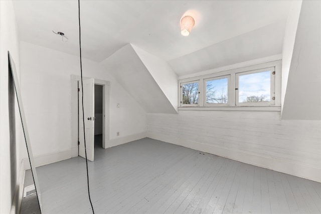 additional living space featuring light wood-style flooring, baseboards, and vaulted ceiling