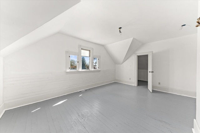 bonus room featuring visible vents, baseboards, hardwood / wood-style flooring, and vaulted ceiling