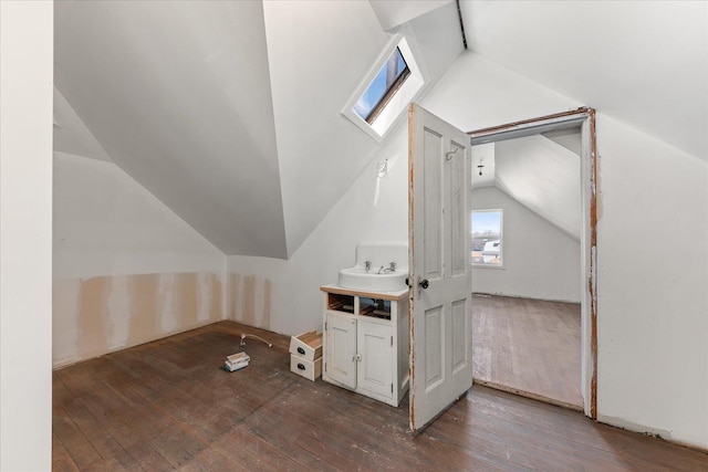 additional living space with hardwood / wood-style flooring and lofted ceiling with skylight
