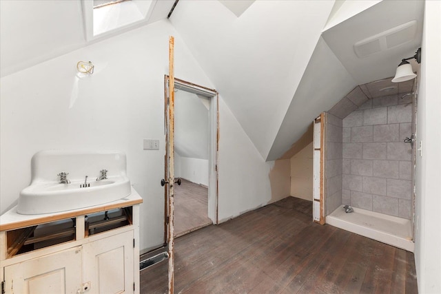 full bath featuring tiled shower, vanity, visible vents, vaulted ceiling, and hardwood / wood-style flooring