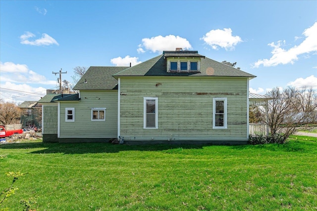 back of house featuring a chimney and a lawn