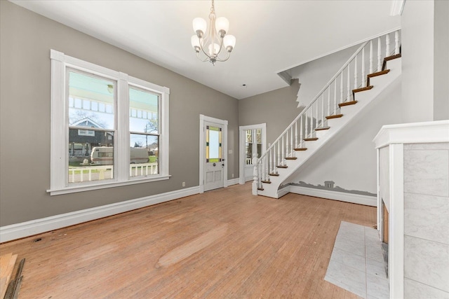 foyer featuring baseboards, stairway, an inviting chandelier, and wood finished floors