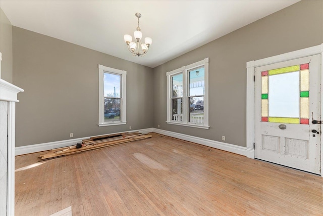 foyer featuring baseboards, a notable chandelier, and wood finished floors
