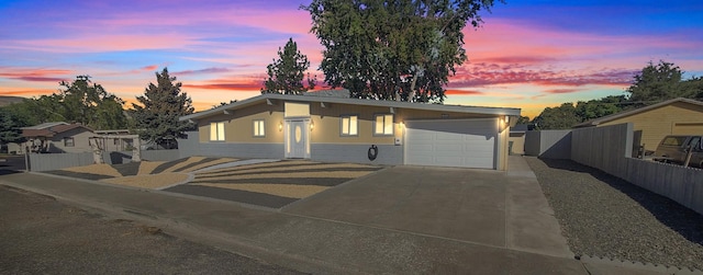 view of front of house featuring an attached garage, driveway, and fence
