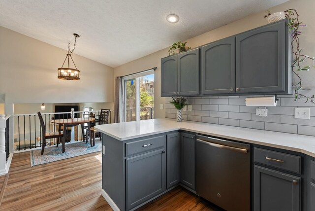 kitchen featuring a peninsula, vaulted ceiling, dishwasher, light countertops, and decorative backsplash