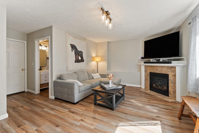 living area featuring baseboards, light wood finished floors, and a tile fireplace