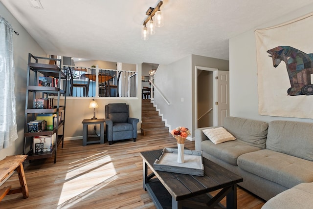 living room featuring baseboards, wood finished floors, and stairs