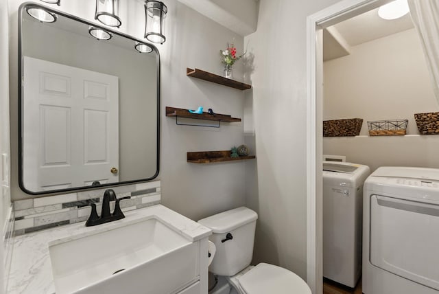 half bath with washer and dryer, vanity, and toilet