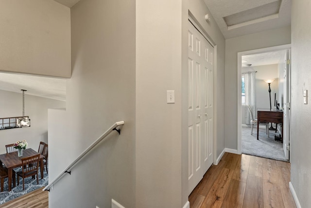 hallway with baseboards, an upstairs landing, and hardwood / wood-style flooring