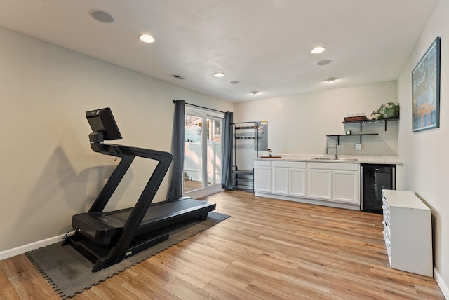 exercise area with a sink, wet bar, light wood-style floors, wine cooler, and recessed lighting