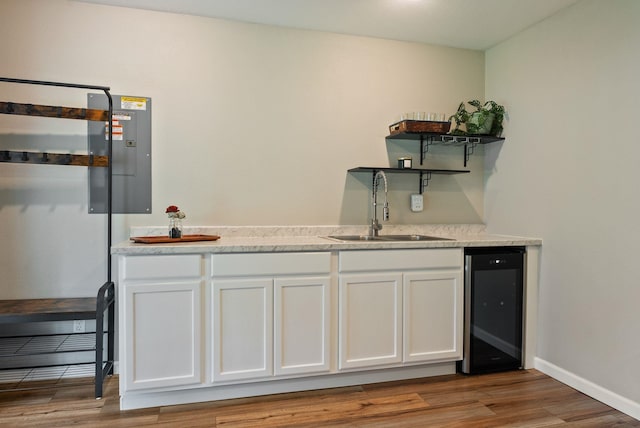 bar with indoor wet bar, wood finished floors, a sink, wine cooler, and baseboards