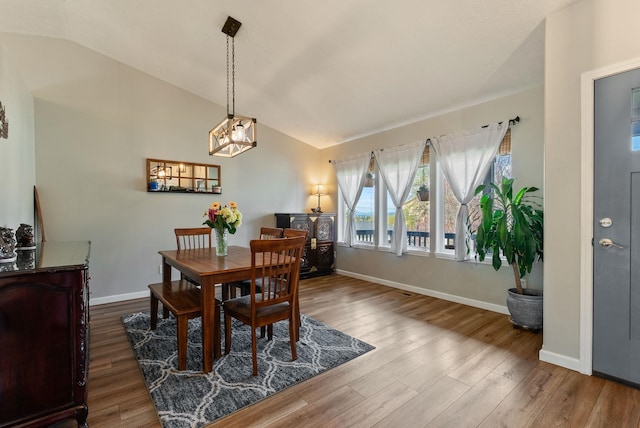 dining room with wood finished floors, an inviting chandelier, baseboards, and lofted ceiling