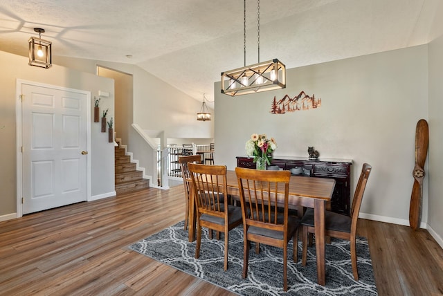 dining space featuring wood finished floors, an inviting chandelier, and vaulted ceiling
