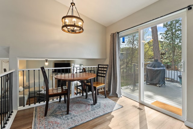 dining room featuring visible vents, high vaulted ceiling, a notable chandelier, and wood finished floors