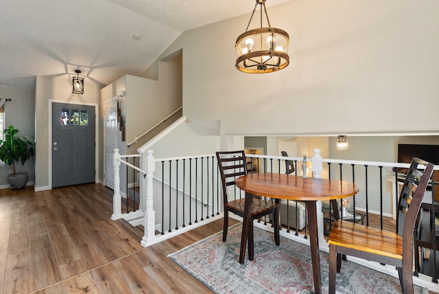 dining room with baseboards, vaulted ceiling, a chandelier, and wood finished floors