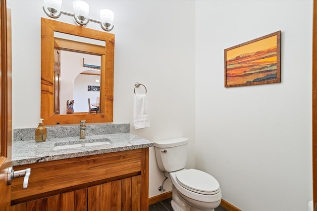 bathroom featuring tile patterned flooring, vanity, baseboards, and toilet