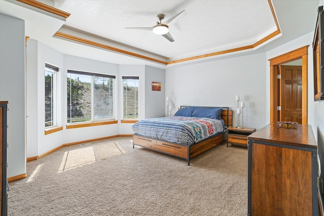 carpeted bedroom with baseboards, a ceiling fan, and a raised ceiling
