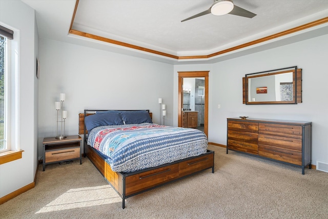 carpeted bedroom featuring ceiling fan, ensuite bathroom, visible vents, a raised ceiling, and baseboards