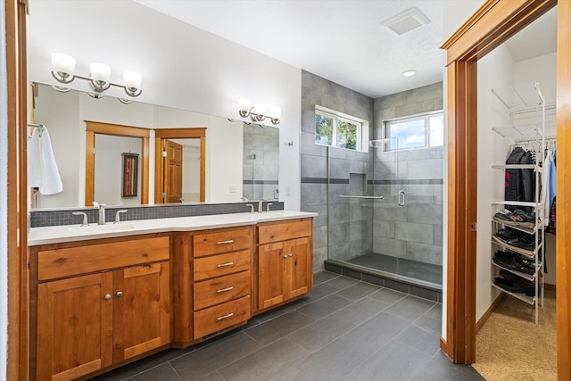 bathroom with a sink, a spacious closet, a shower stall, and double vanity
