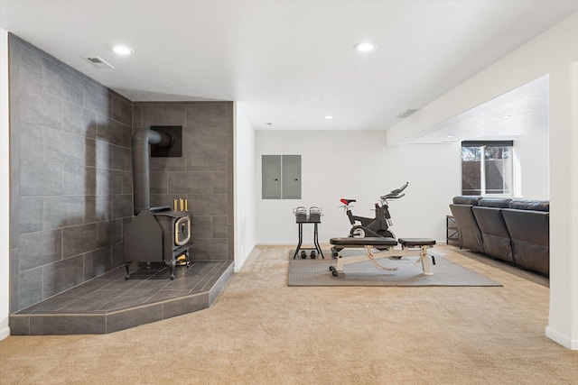 exercise area featuring carpet floors, a wood stove, visible vents, and recessed lighting