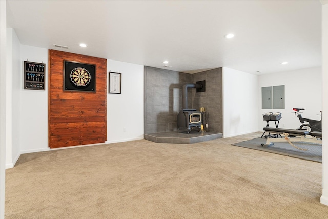 workout area with carpet floors, a wood stove, electric panel, and recessed lighting