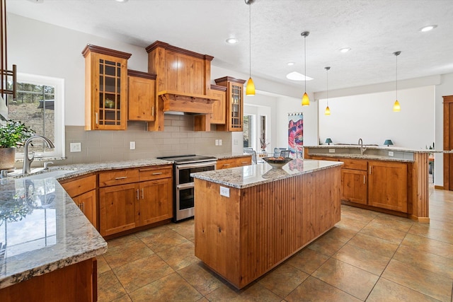 kitchen with custom exhaust hood, tasteful backsplash, a sink, double oven range, and a kitchen island