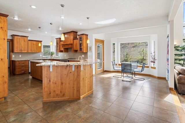 kitchen featuring a kitchen breakfast bar, glass insert cabinets, brown cabinets, and backsplash