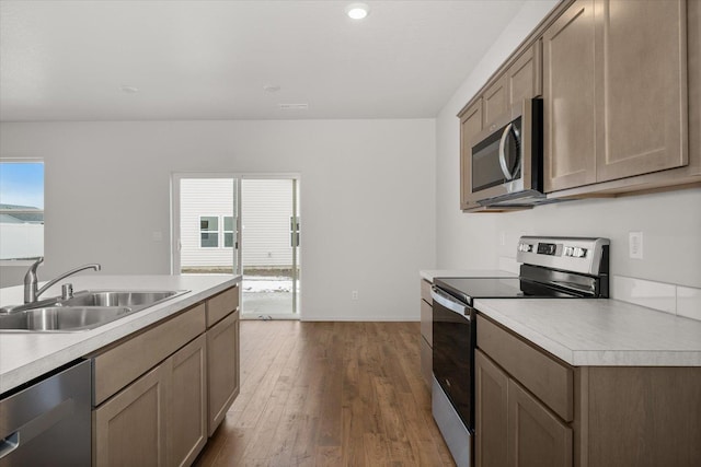 kitchen with dark wood-type flooring, light countertops, a sink, and appliances with stainless steel finishes