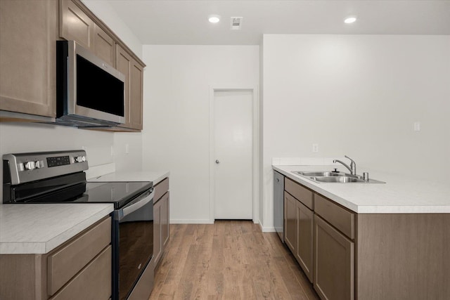 kitchen with recessed lighting, light wood-style flooring, light countertops, stainless steel appliances, and a sink