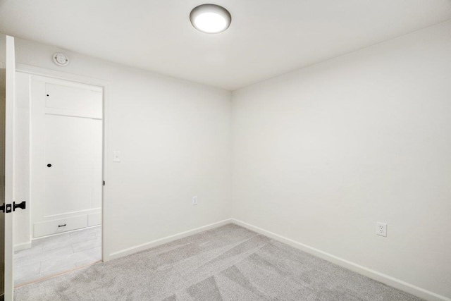 empty room featuring light colored carpet and baseboards