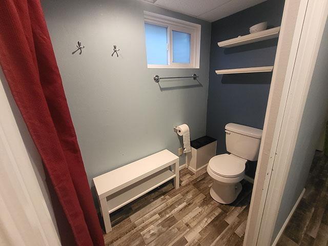 bathroom with baseboards, wood finished floors, and toilet