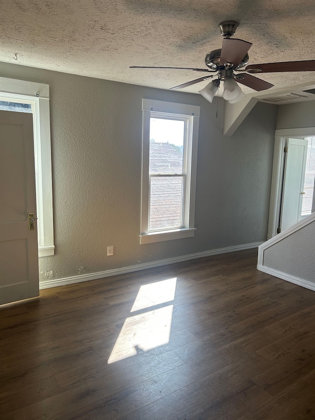 empty room featuring a textured wall, wood finished floors, and a textured ceiling