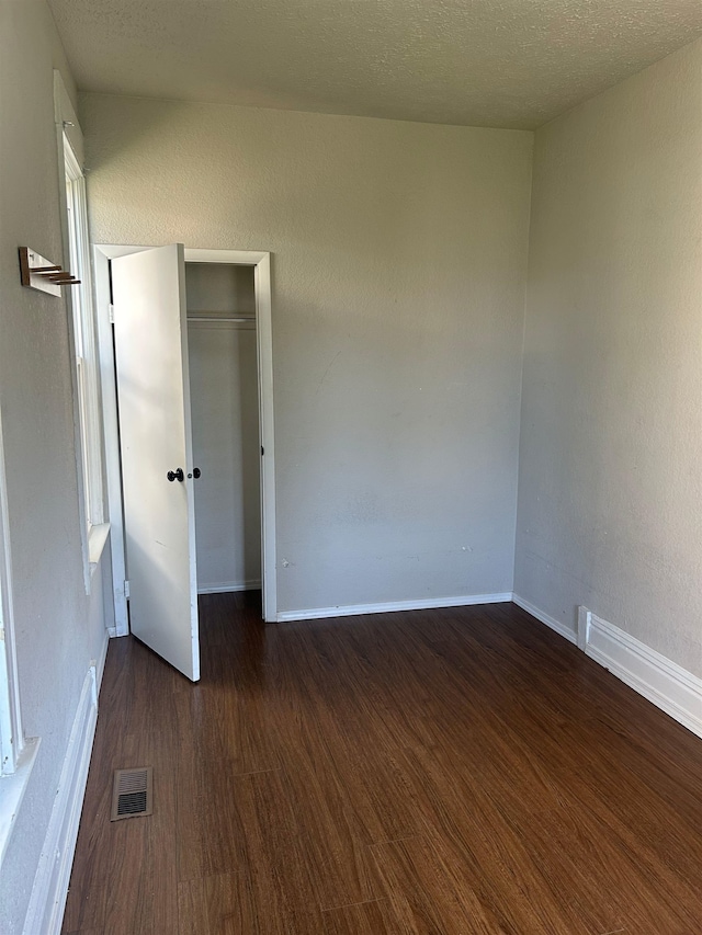 empty room with dark wood-type flooring, baseboards, and visible vents