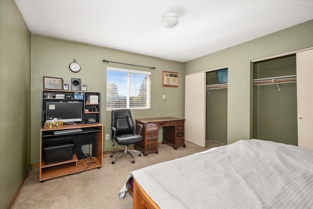 bedroom featuring carpet flooring, an AC wall unit, and multiple closets