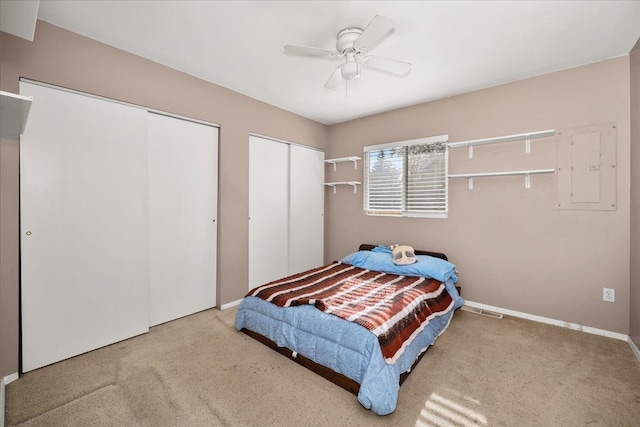 bedroom featuring multiple closets, carpet flooring, baseboards, and electric panel