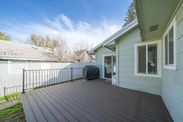 wooden deck with a fenced backyard and area for grilling