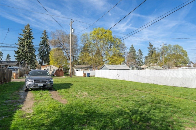 view of yard featuring fence, an outbuilding, and a storage unit