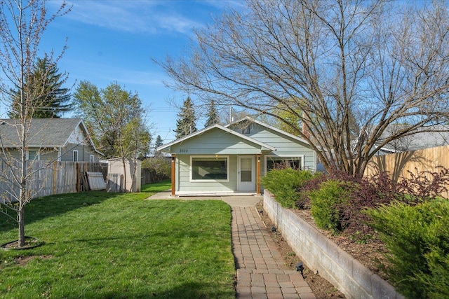 bungalow-style home featuring a fenced backyard, a front yard, and an outdoor structure