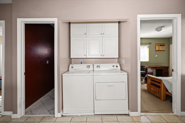 clothes washing area with light tile patterned floors, baseboards, washing machine and clothes dryer, and cabinet space