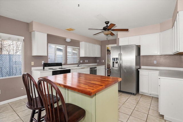 kitchen featuring light tile patterned floors, ceiling fan, stainless steel refrigerator with ice dispenser, range with electric stovetop, and wood counters