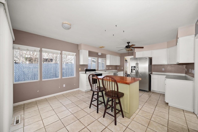 kitchen featuring a center island, wood counters, light tile patterned flooring, and stainless steel appliances
