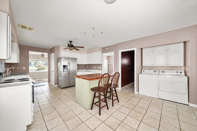 kitchen with a ceiling fan, butcher block counters, stainless steel refrigerator with ice dispenser, range with electric stovetop, and washer and clothes dryer