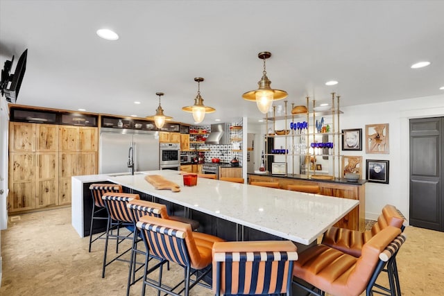 kitchen with pendant lighting, wall chimney exhaust hood, high end appliances, recessed lighting, and a large island