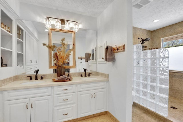 full bath with a textured ceiling, a walk in shower, and a sink