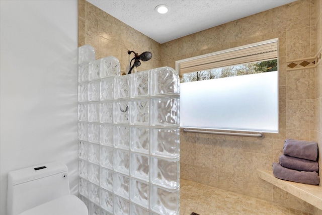 full bath featuring toilet, a textured ceiling, a walk in shower, and a healthy amount of sunlight