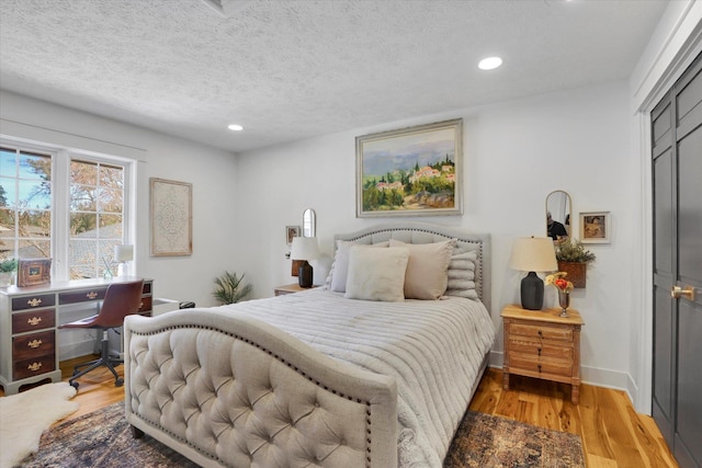 bedroom with recessed lighting, light wood-style flooring, a textured ceiling, and baseboards