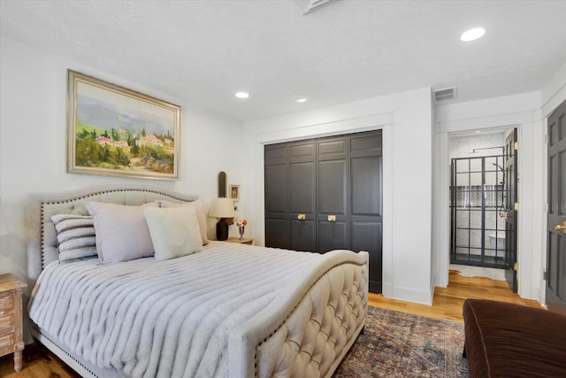 bedroom featuring visible vents, recessed lighting, a closet, and wood finished floors