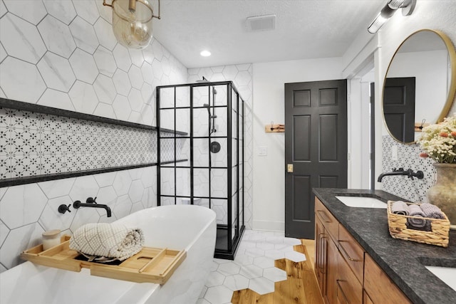 bathroom with double vanity, a soaking tub, a textured ceiling, a shower stall, and a sink