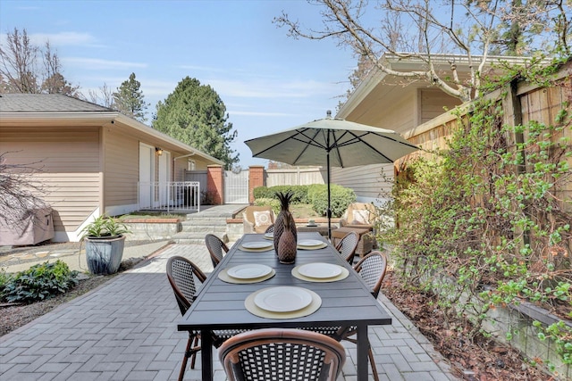 view of patio featuring outdoor dining space, fence, and a gate