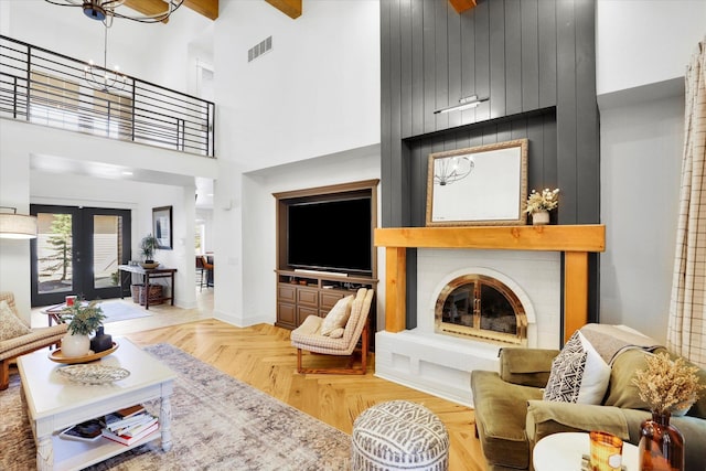 living room with french doors, a fireplace, a towering ceiling, and visible vents